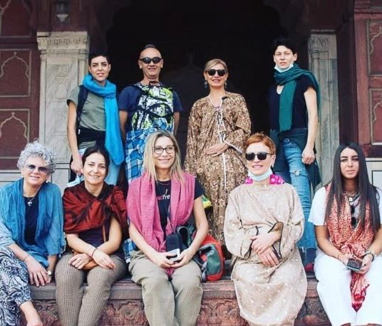 Un gruppo di allieve e allievi in viaggio in India, seduti davanti a un portale scolpito